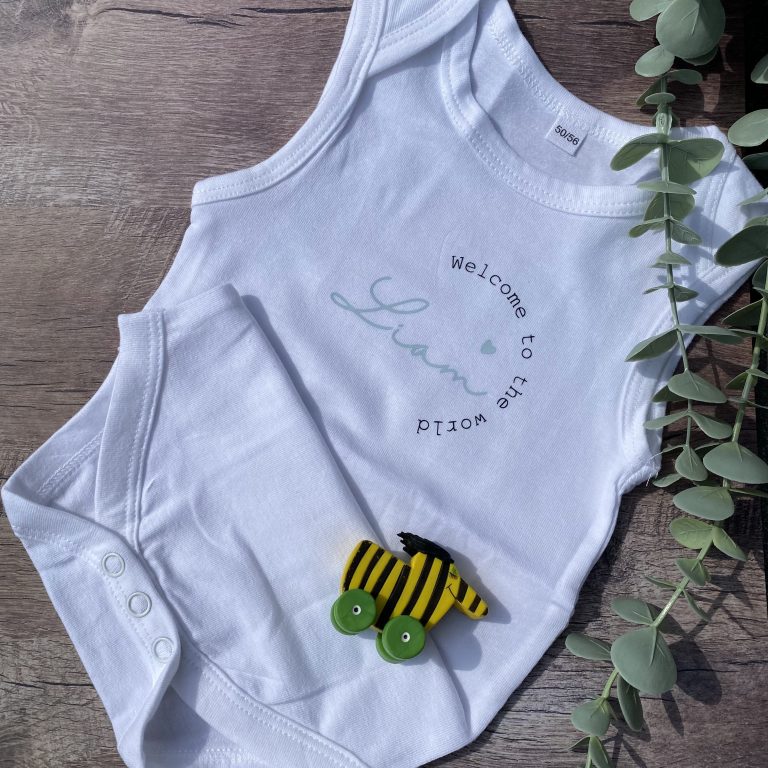 Weißer Baby-Body für Liam mit „Welcome to the world“-Aufdruck